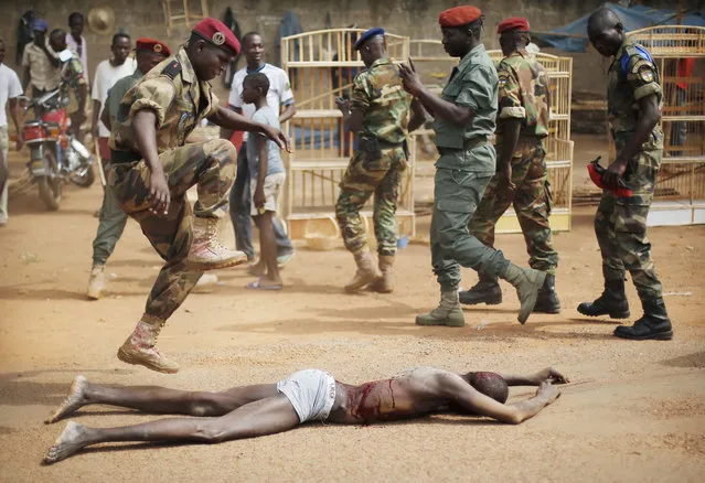 In this Wednesday February 5, 2014 photo, a FACA (Central African Armed Forces) officer jumps on the lifeless body of a suspected Muslim Seleka militiaman moments after Central African Republic Interim President Catherine Samba-Panza addressed the troops in Bangui, Central African Republic. A sweeping United Nations report has identified hundreds of human rights violations in Central African Republic that may amount to war crimes. The Tuesday may 30, 2017, report comes amid growing fears that the country terrorized by multiple armed groups is once again slipping into the sectarian bloodshed that left thousands dead between late 2013 and 2015. (Photo by Jerome Delay/AP Photo)