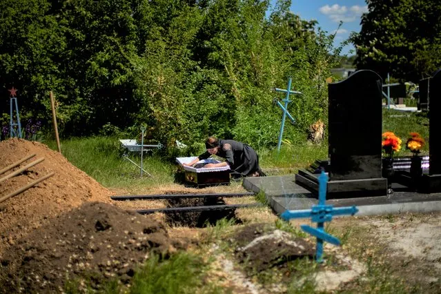 Iuliia Loseva cries over the coffin of her husband Volodymyr Losev, 38, during his funeral at a cemetery in Zorya Truda, Odesa region, Ukraine, Monday, May 16, 2022. Volodymyr Losev, a Ukrainian volunteer soldier, was killed on May 7 when the military vehicle he was driving ran over a mine in eastern Ukraine. (Photo by Francisco Seco/AP Photo)