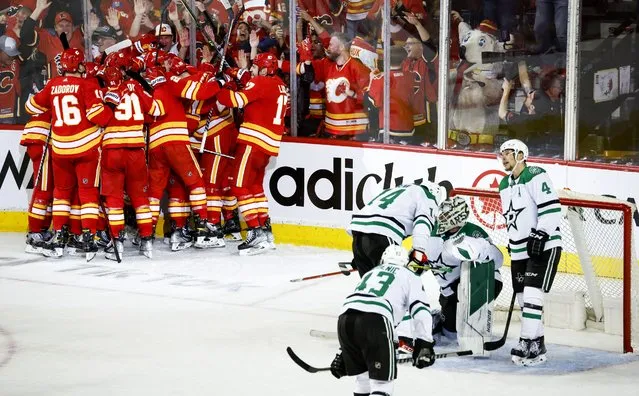 Dallas Stars goalie Jake Oettinger, second from right, is consoled by teammates as Calgary Flames celebrate following overtime NHL playoff hockey action in Calgary, Alberta, Sunday, May 15, 2022. (Photo by Jeff McIntosh/The Canadian Press via AP Photo)