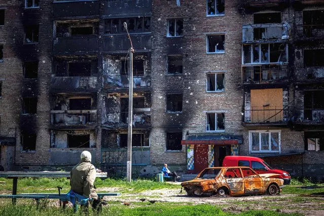 Local residents sit next next to a damaged apartment building in the town of Irpin, near Kyiv, on May 31, 2022,amid the Russian invasion of Ukraine. (Photo by Dimitar Dilkoff/AFP Photo)