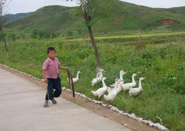 A kid with his gooses on the highway side. Most of the time people use the highway for their daily activities and are surprised to see cars or buses on it. (Photo by Eric Lafforgue/Exclusivepix Media)