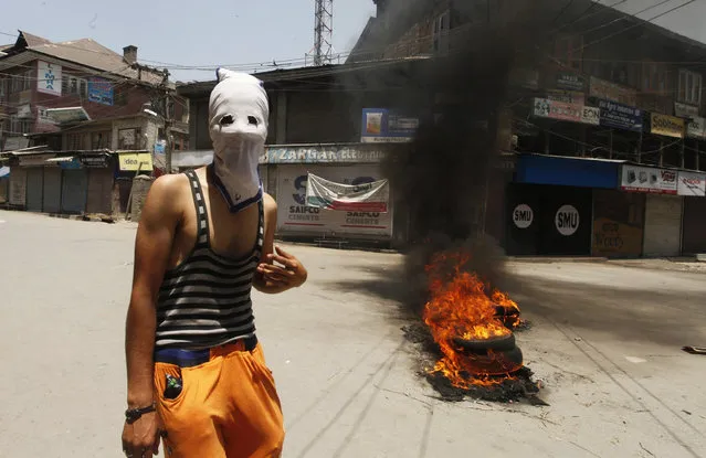 A masked Kashmiri Muslim stands near burning tires during a protest in Srinagar, the summer capital of Indian Kashmir, 25 June 2016. According to local news reports, clashes broke out between the Indian Police and protesters in Maisuma area of Srinagar when a protest march of separatists was not allowed to reach Lal Chowk, the city centre. The separatists had called for a protest in Lal Chowk against what they call conspiracies to change the demography of the Muslim-majority Jammu Kashmir by setting up Sainik colonies (Colonies for retired Indian Army men) and separate township for displaced Kashmiri Pandits (Hindus). (Photo by EPA/Stringer)