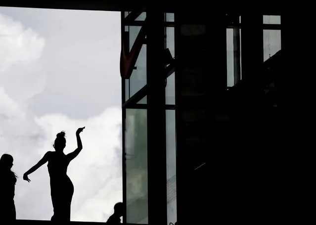 A girl dances in front of a window at the Porta Nuova business district in Milan, Italy, Friday, June 30, 2017. (Photo by Luca Bruno/AP Photo)
