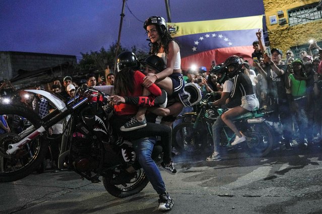 A motorcyclist carries three young woman as he performs a wheelie on his motorbike during an exhibition in the Chapellin neighborhood of Caracas, Venezuela, Sunday, June 12, 2022. (Photo by Matias Delacroix/AP Photo)