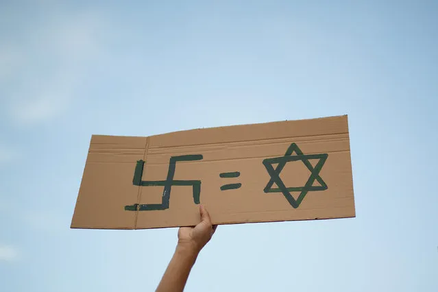 A Pro-Palestinian demonstrator holds a placard with the symbols “Swastika equal to Star of David” during a demonstration on July 17, 2014 in Madrid, Spain. (Photo by Pablo Blazquez Dominguez/Getty Images)