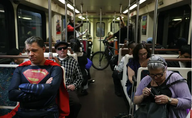 In this Tuesday, May 16, 2017 photo, superhero impersonator Justin Harrison, left, rides a Metro train wearing a Superman costume on his way to Hollywood Boulevard in Los Angeles. “I always go out in a costume”, said Harrison. “I love seeing people happy and seeing them smile”. (Photo by Jae C. Hong/AP Photo)