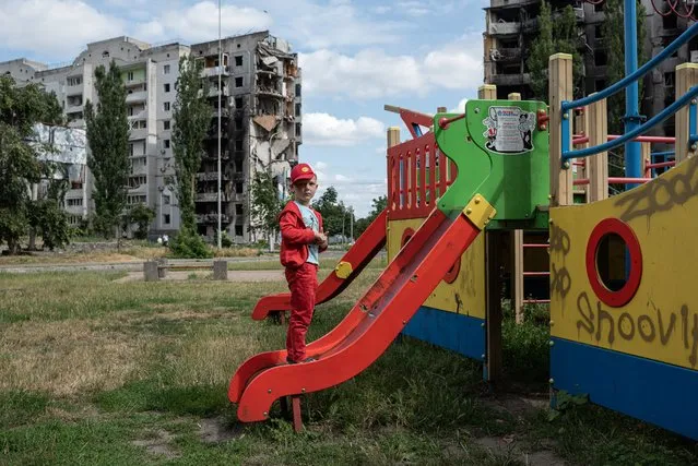 A boy is seen on the playground next to a heavily damaged apartment building on July 7, 2022 in Borodianka, Ukraine. The region around Ukraine's capital continues to recover from Russia's aborted assault on Kyiv, which turned many communities into battlefields. (Photo by Alexey Furman/Getty Images)