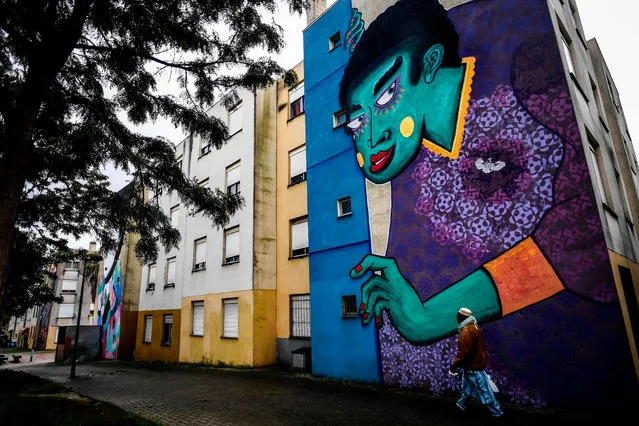 A resident of Quinta do Mocho neighbourhood walk past a mural by French artist Stew, in Sacavem, outskirts of Lisbon, on November 11, 2019. (Photo by Patricia De Melo Moreira/AFP Photo)