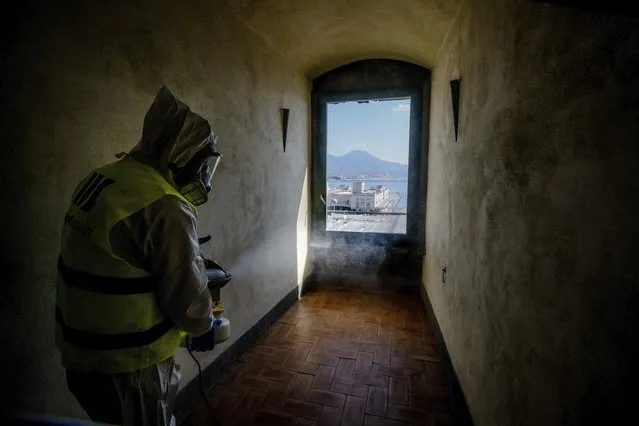 A worker sprays disinfectant as sanitization operations against Coronavirus are carried out in the museum hosted by the Maschio Angioino medieval castle, in Naples, Italy, Tuesday, March 10, 2020. (Photo by Alessandro Pone/LaPresse via AP Photo)