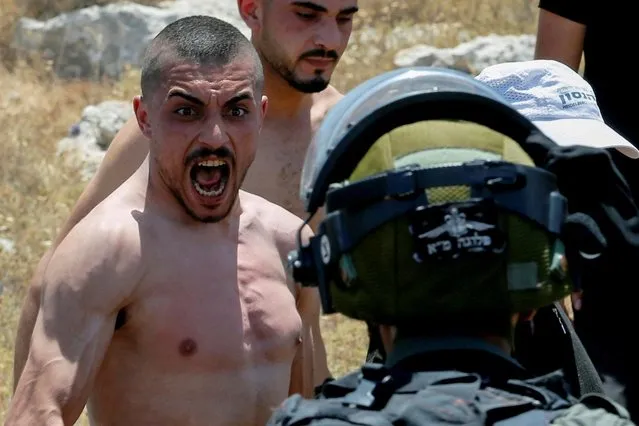 A Palestinian man reacts as he confronts Israeli forces during a protest against Israeli settlement activity near Hebron in the Israeli-occupied West Bank on June 11, 2022. (Photo by Mussa Qawasma/Reuters)