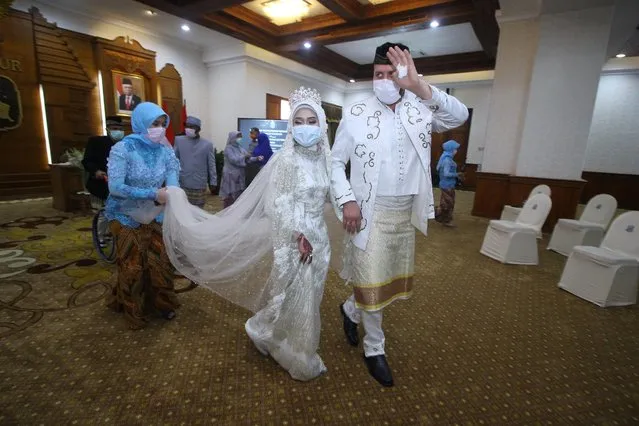 Indonesian bride and groom wearing protective face masks on their wedding day reacts, amid the coronavirus disease (COVID-19) outbreak in Surabaya, East Java Province, Indonesia on March 25, 2020. (Photo by Moch Asim/Antara Foto via Reuters)