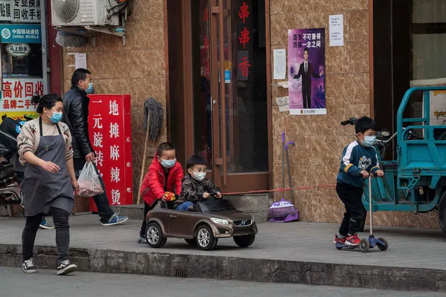 Boys wearing face masks amid the COVID-19 coronavirus outbreak play along a street in Beijing on March 29, 2020. (Photo by Nicolas Asfouri/AFP Photo)