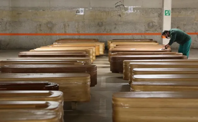 A worker checks coffins, most of them containing the bodies of COVID-19 victims, in the parking of a funeral parlour, during the coronavirus disease (COVID-19) outbreak, in Barcelona, Spain on April 2, 2020. (Photo by Nacho Doce/Reuters)