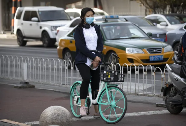 A cyclist pauses during a national moment of mourning for victims of the coronavirus, in Beijing on Saturday, April 4, 2020. With air raid sirens wailing and flags at half-staff, China on Saturday held a three-minute nationwide moment of reflection to honor those who have died in the coronavirus outbreak, especially “martyrs” who fell while fighting what has become a global pandemic. (Photo by Mark Schiefelbein/AP Photo)