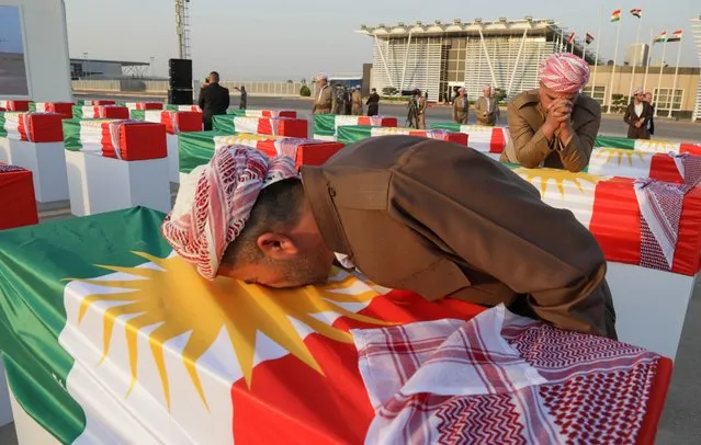 A man mourns over a coffin draped with the Kurdish flag and containing the remains of a victim of the Anfal massacre, during a ceremony in Arbil, the capital of Iraq's northern Kurdish autonomous region, on July 30, 2022. The Anfal massacre campaign, carried out by Saddam Hussein's forces between 1986 and 1989, saw nearly 180,000 Kurds killed and more than 3,000 villages destroyed. (Photo by Safin Hamed/AFP Photo)