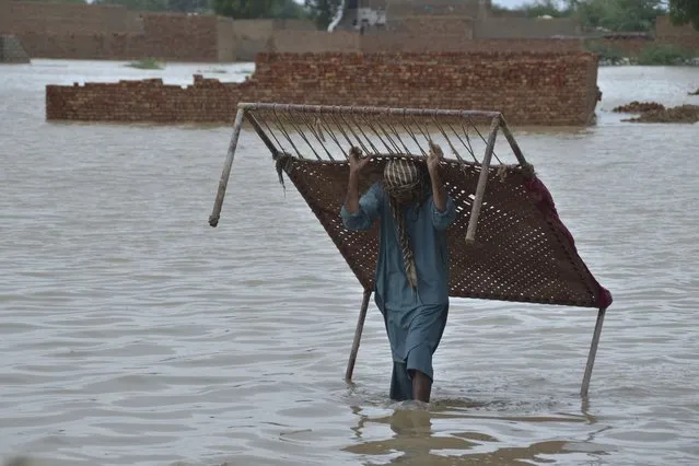 A man carries cot after he salvaged it from his flood-hit home in Jaffarabad, a district of Pakistan's southwestern Baluchistan province, Thursday, August 25, 2022. (Photo by Zahid Hussain/AP Photo)