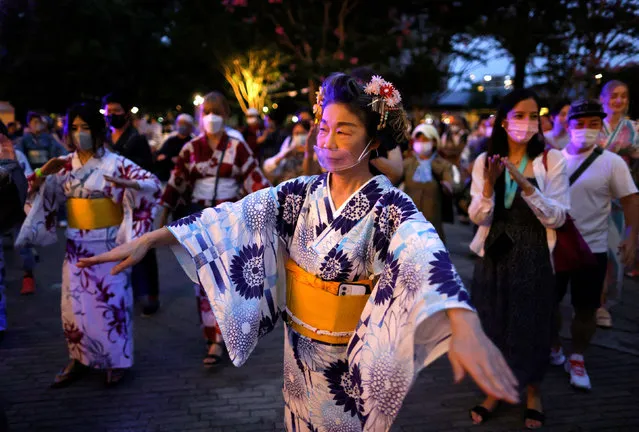Revelers clad in yukatas, summer kimonos, wearing protecive face masks take part in a Bon Odori festival, a Japanese traditional dance which originates from Buddhism, amid the coronavirus disease (COVID-19) pandemic, at Nakano ward in Tokyo, Japan on August 6, 2022. (Photo by Issei Kato/Reuters)