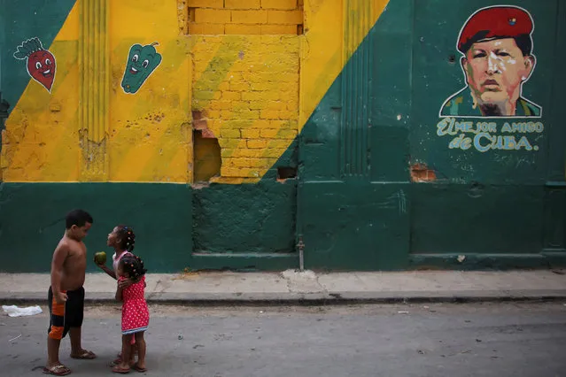 Children play next to an image depicting Venezuela's late president Hugo Chavez on a wall that reads “The best friend of Cuba”, in downtown Havana, Cuba, July 8, 2016. (Photo by Alexandre Meneghini/Reuters)