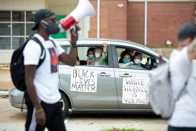 A family in a car looks on as protesters march against the Confederate Monument carved into granite at Stone Mountain Park, in Stone Mountain, Georgia, U.S. June 16, 2020. (Photo by Dustin Chambers/Reuters)
