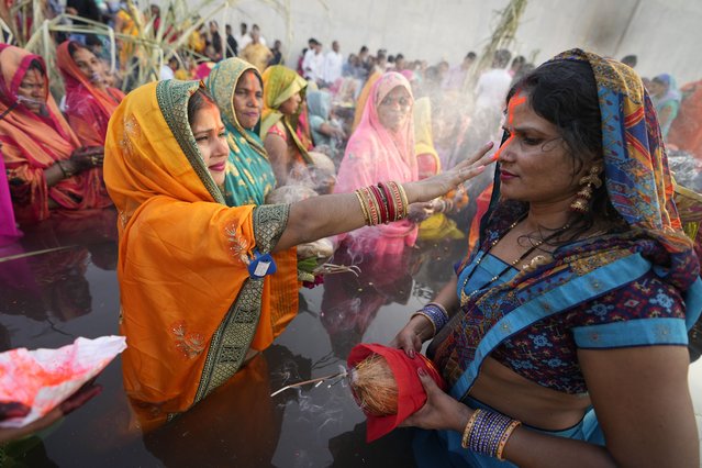 Hindu devotees perform rituals at sunset on the banks of the River Sabarmati during Chhath Puja festival in Ahmedabad, India, Sunday, October 30, 2022. During Chhath, an ancient Hindu festival, rituals are performed to thank the Sun god for sustaining life on earth. (Photo by Ajit Solanki/AP Photo)