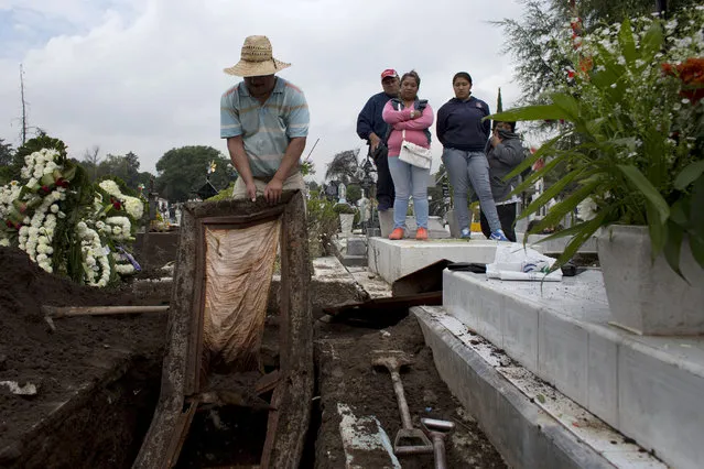 In this Sept. 17, 2014 photo, relatives watch as the body of a mother and sister is exhumed to free up space for a new burial, at a nearly-full San Isidro cemetery in northern Mexico City. (AP Photo/Rebecca Blackwell)