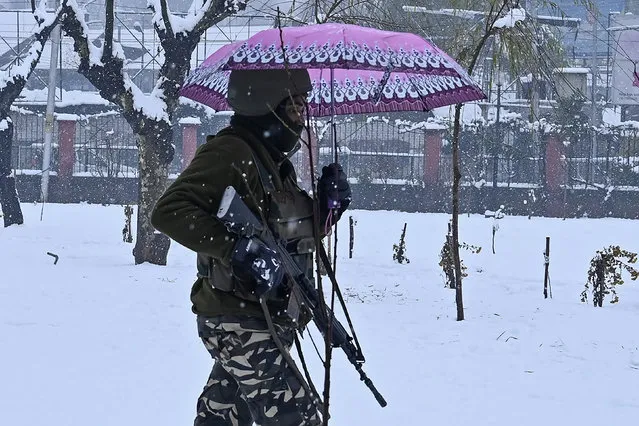 An Indian paramilitary trooper carries an umbrella as he walks through a park during snowfall in Srinagar on December 13, 2019. (Photo by Tauseef Mustafa/AFP Photo)