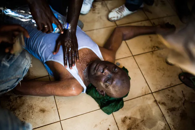 Protestors  pour  water on a  injured man near the parliament building in Burkina Faso as people protest  against their longtime president Blaise Compaore who is  seeking another term in Ouagadougou, Burkina Faso, Thursday, October 30, 2014. (Photo by Theo Renaut/AP Photo)