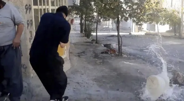 In this image from video provided by Hengaw Organization for Human Rights, a protester reacts after a water container was hit by a bullet during a protest in Javanroud, a Kurdish town in western Iran, Monday, November 21, 2022. (Photo by Hengaw Organization for Human Rights via AP Photo)