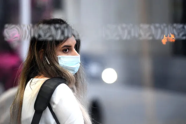 A woman wearing a face mask waits for a bus on August 31, 2020 in Auckland, New Zealand. Face coverings are now compulsory for all New Zealanders over the age of 12 on public transport or planes under current Alert Level restrictions in place across the country. Auckland is currently at Alert Level 2.5 while the rest of New Zealand is at Alert Level 2. (Photo by Hannah Peters/Getty Images)