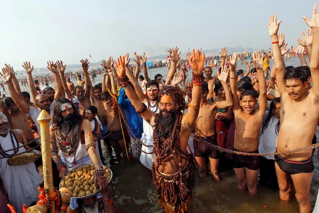 Sadhus or Hindu holy men and devotees pray as they take a holy dip at Sangam, the confluence of the Ganges, Yamuna and Saraswati rivers, during Magh Mela festival in Allahabad, India, January 15, 2018. (Photo by Jitendra Prakash/Reuters)