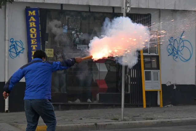 A supporter of the ruling Movement To Socialism (MAS) fires a petard to opposers to President Luis Arce during a protest march “for democracy, freedom, and justice” demanding the release of the governor of Santa Cruz, Luis Fernando Camacho, in La Paz, on January 10, 2023. (Photo by Aizar Raldes/AFP Photo)