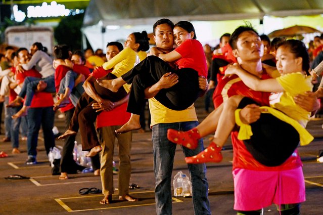 Men carry women during a competition and Guinness World Record attempt in Phnom Penh on March 8, 2024. Hundreds of Cambodian couples braved sticky tropical heat to set an unusual new world record – for most people performing a “bridal carry” at the same time. (Photo by Tang Chhin Sothy/AFP Photo)