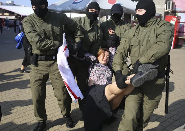 Police officer detain a woman with an old Belarusian national flag during an opposition rally to protest the official presidential election results in Minsk, Belarus, Saturday, September 26, 2020. (Photo by TUT.by via AP Photo)