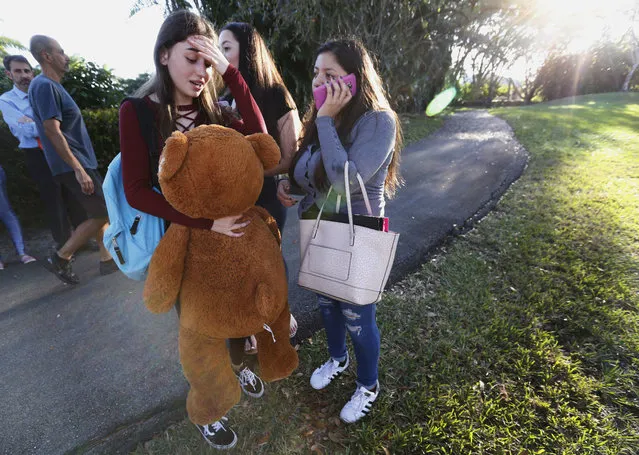 Students wait to be picked up after a shooting at Marjory Stoneman Douglas High School in Parkland, Fla., Wednesday, February 14, 2018. A shooter opened fire at the Florida high school Wednesday, killing people, sending students running out into the streets and SWAT team members swarming in before authorities took the shooter into custody. (Photo by Wilfredo Lee/AP Photo)