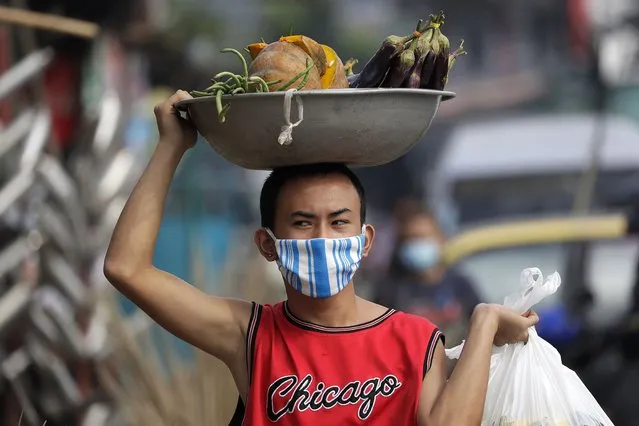A man wears a mask to curb the spread of the coronavirus as he peddles vegetables at the outskirts of Manila, Philippines on Friday, September 25, 2020. The brooms are sold from P30-P200 (about US 50 cents to US$4) each. (Photo by Aaron Favila/AP Photo)