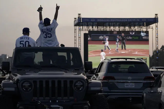 Mike Kim, left, and Jacob Zelaya cheer in their vehicle outside Dodger Stadium and watch the television broadcast of Game 1 of the 2020 World Series between the Los Angeles Dodgers and the Tampa Bay Rays in Tuesday, October 20, 2020, in Los Angeles. Due to the spread of COVID-19, all of the 2020 World Series games will be played in Arlington, Texas. (Photo by Ashley Landis/AP Photo)