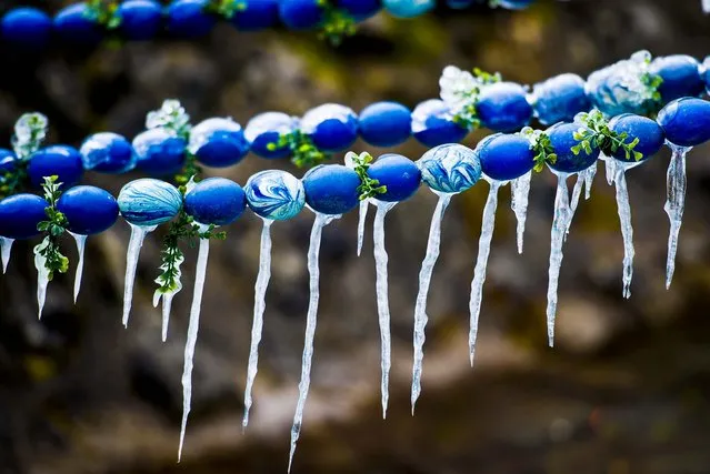 Icicles hang on a decorated Easter fountain in Bieberbach, Germany, on March 24, 2013. The Easter well is a German tradition of decorating public wells or fountains with Easter eggs for the holiday. (Photo by David Ebener/Associated Press)
