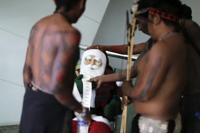 Indigenous men look at a Santa Claus doll at the entrance of the building of the National Confederation of Agriculture building during a protest against the approval of the Proposed Constitutional Amendment (PEC 215) in Brasilia December 5, 2014. Indigenous protesters are demonstrating against the possible appointment of Senator Katia Abreu to the Ministry of Agriculture in Brasilia. (Photo by Ueslei Marcelino/Reuters)