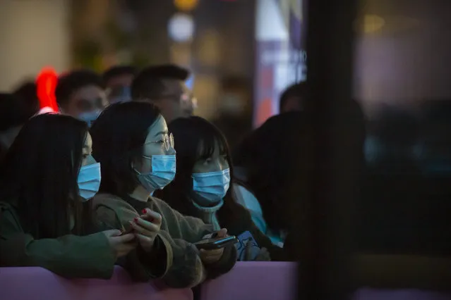 People wearing face masks to protect themselves against the coronavirus watch a livestreamer perform at a shopping mall in Beijing, Friday, October 30, 2020. Chinese authorities are increasingly confident they have contained a COVID-19 outbreak in the country's far western region of Xinjiang. (Photo by Mark Schiefelbein/AP Photo)