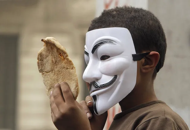 An Egyptian boy wearing a Guy Fawkes Mask holds bread, a symbol of poverty, during an anti-Muslim Brotherhood demonstration in Cairo, Egypt, on March 22, 2013. Thousands of protesters from different areas of Cairo marched on Friday to express their rejection of the Muslim Brotherhood and President Mohammed Morsi's rule. (Photo by Amr Nabil/AP Photo /The Atlantic)