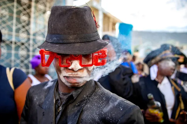 A man who is said to be possessed with the Gede spirit performs a ritual at the National Cemetery during ceremonies honoring the Haitian Voodoo spirit of Baron Samdi and Gede on the Day of the Dead in Port-au-Prince, Haiti, Sunday, November 1, 2020. Followers of Voodoo with their faces covered in white powder, wearing hats and dressed in black, white and purple clothes join the Fete Gede celebration of the spirits equivalent to the Roman Catholic festivity of the Day of the Dead and Day of All Saints. (Photo by Dieu Nalio Chery/AP Photo)