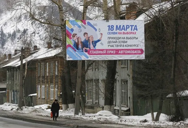 A woman walks past a board, which informs of the upcoming presidential election and calls to vote, in Krasnoyarsk, Russia March 16, 2018. The board reads “March 18. Selfies during the election. Come up for the election. Take a selfie. Take part in the contest. The top prize is an automobile”. (Photo by Ilya Naymushin/Reuters)