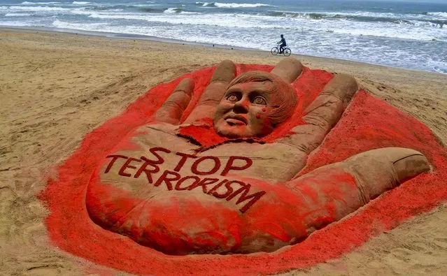 A cyclist pedals past a sculpture at the golden sea beach in Puri, India, with a message against terrorism following attacks in Boston and Bangalore, on April 17, 2013. (Photo by Associated Press)