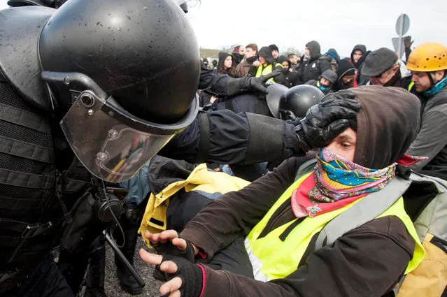 Regional riot policemen face pro-independence protesters as security forces try to clear AP-7 toll road near the town of Figueres, in Girona, Catalonia, northeastern Spain, 27 March 2018. The demonstrators had blocked off the highway to protest against the arrest of fugitive former Catalan regional President Carles Puigdemont in Germany. Some one thousand vehicles were affected by the protest held close to the French border. (Photo by Robin Townsend/EPA/EFE)