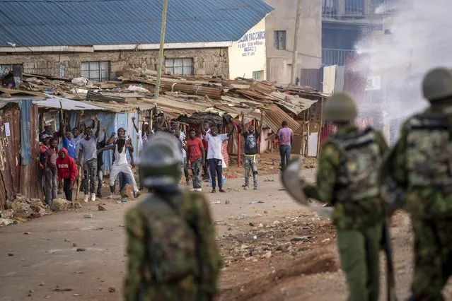 Protesters shout at police as they demonstrate in the Kibera slum of Nairobi, Kenya Monday, March 20, 2023. Hundreds of opposition supporters took to the streets of the Kenyan capital over the result of the last election and the rising cost of living, in protests organized by the opposition demanding that the president resigns from office. (Photo by Ben Curtis/AP Photo)