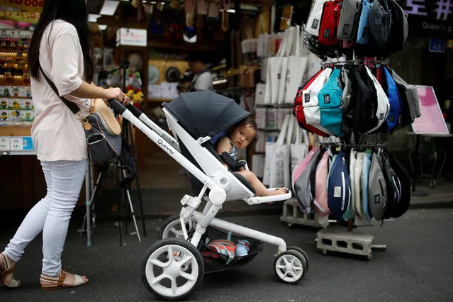 A woman pushing her baby in a stroller shops in the Hongdae area of Seoul, South Korea, June 29, 2016. Picture taken June 29, 2016. (Photo by Kim Hong-Ji/Reuters)