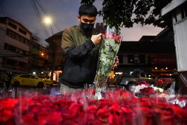 A man prepares packages of roses ahead of Valentine's Day at a market in Bangkok, Thailand on February 13, 2023. (Photo by Chalinee Thirasupa/Reuters)