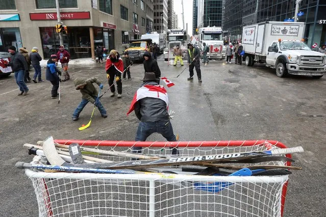 People play street hockey on a closed street, as truckers and supporters continue to protest coronavirus disease (COVID-19) vaccine mandates, in Ottawa, Ontario, Canada, February 6, 2022. (Photo by Lars Hagberg/Reuters)