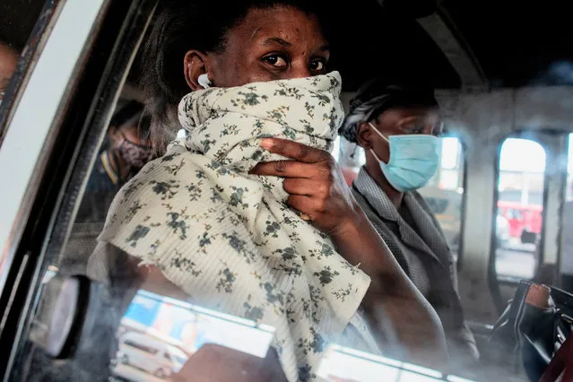 A commuter looks on as she protects herself with a scarf while sitting with other passengers in a mini bus taxi at the Bara taxi rank in Soweto, Johannesburg, on December 17, 2020. (Photo by Luca Sola/AFP Photo)