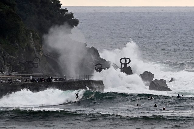Waves crash against the “Peine del Viento” (Wind Comb) sculptures by Spanish artist Eduardo Chillida as surfers ride nearby during a weather alert for rough seas in San Sebastian, northern Spain, on August 26, 2025. (Photo by Ander Gillenea/AFP Photo)